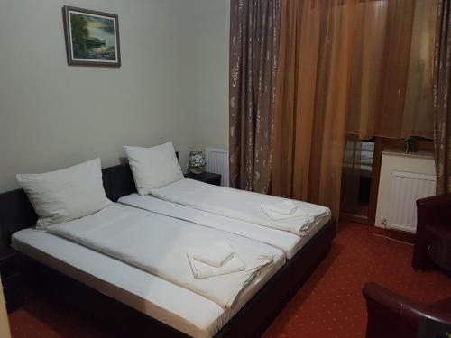 a bedroom with a bed with white sheets and a window at Extra Jezero rooms in Palić