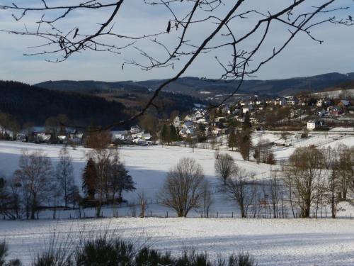 a snow covered field with a town in the distance at Ferienhaus Broche in Hilchenbach