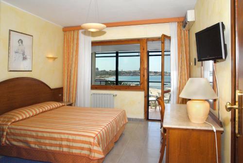 a hotel room with a bed and a television at Hotel Florida in Alghero