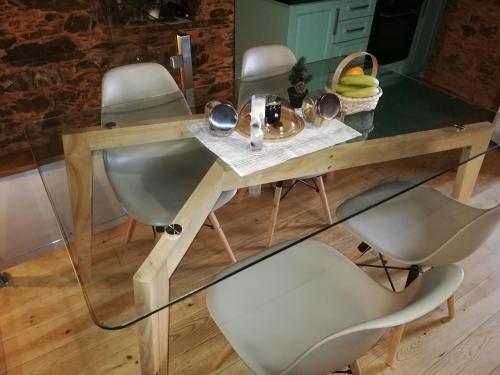 a glass table with chairs and a table with food on it at Casinha do Talasnal in Lousã