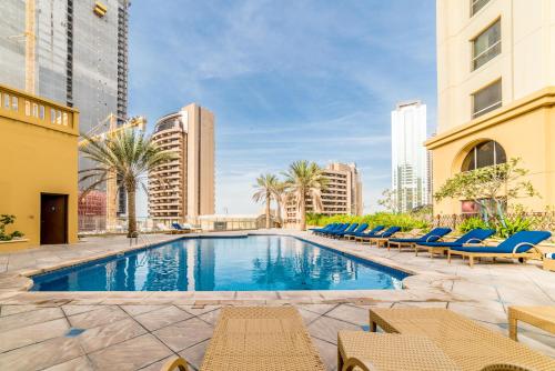 a swimming pool with lounge chairs and buildings at Royal Beach Residence in Dubai