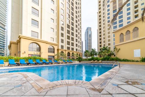 a swimming pool with chairs and buildings at Royal Beach Residence in Dubai