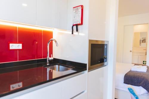 ポルトにあるAPOSENTUS - Your Home at Pinheiro's Studioのキッチン(シンク付)、テレビが備わります。