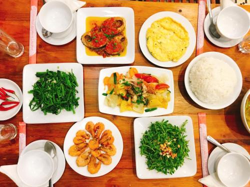 a wooden table with plates of food on it at Sunbay Homestay Cu Lao Cham in Tân Hiệp