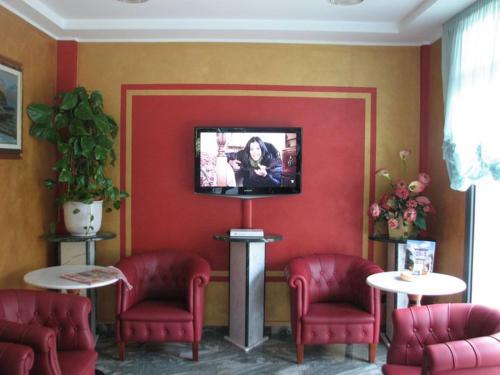 a waiting room with red chairs and a flat screen tv at Hotel Smeraldo in Lido di Camaiore