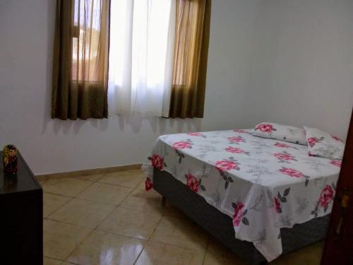 - une chambre avec un lit doté d'une couverture fleurie dans l'établissement Casa conforto, à Lavrinhas