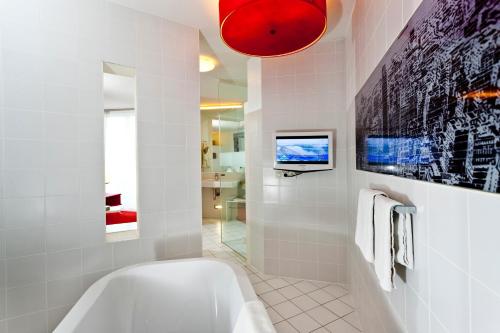 a bathroom with a tub and a tv on the wall at Casinohotel Velden in Velden am Wörthersee