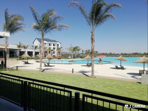 a view of a swimming pool with palm trees at The Blyde - Crystal Lagoon Penthouse Apartment in Pretoria