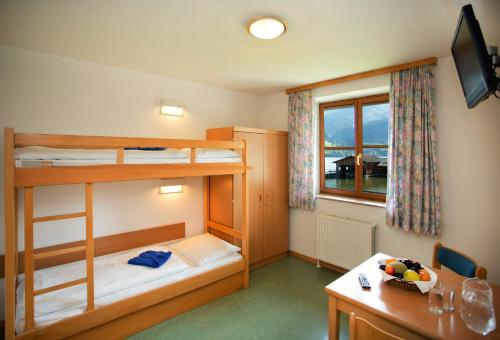 a room with two bunk beds and a table and a desk at Junges Hotel Zell am See in Zell am See