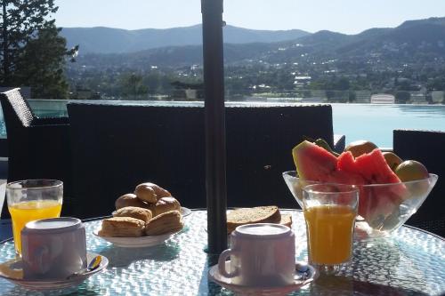 een tafel met een fruitschaal en twee glazen sinaasappelsap bij Domus Lake Resorts in Villa Carlos Paz