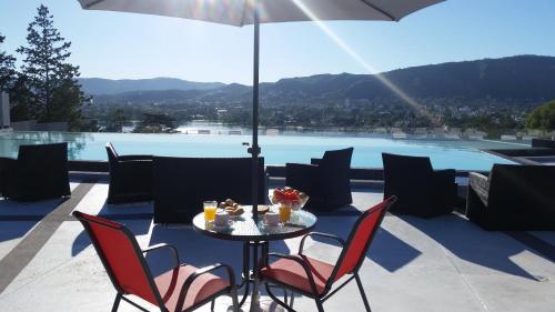 Una mesa con sillas y una sombrilla en un patio. en Domus Lake Resorts, en Villa Carlos Paz