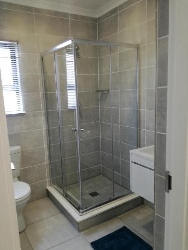 a shower with a glass door in a bathroom at The Blyde - Crystal Lagoon Penthouse Apartment in Pretoria