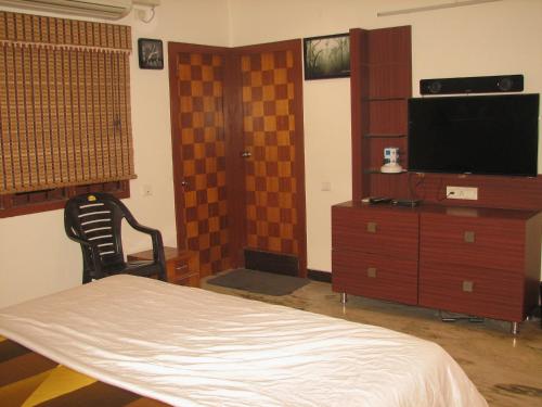 Atithi Comfort Homes (Exclusively for families) - Royal في فيساخاباتنام: غرفة نوم بسرير وخزانة وتلفزيون