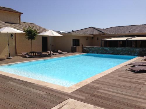 a swimming pool with chairs and umbrellas next to a house at Osteria A Stalla Sischese & Spa in Sisco