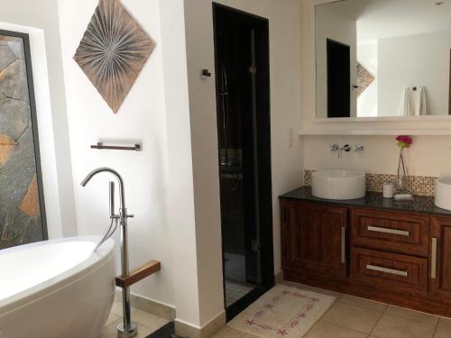 a bathroom with a tub and a sink and a mirror at Villa Astreia in Bel Ombre