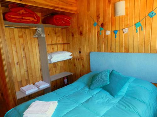 a bedroom with a blue bed in a wooden wall at Casita de Madera in San Carlos de Bariloche