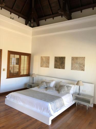 a bedroom with a large white bed with two tables at Villa Astreia in Bel Ombre