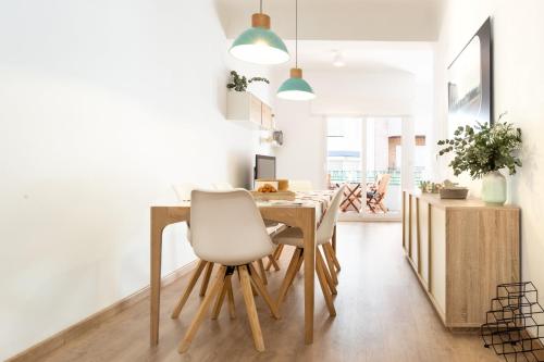 uma sala de jantar com uma mesa de madeira e uma cadeira branca em Diseño y confort en el centro de Alicante em Alicante