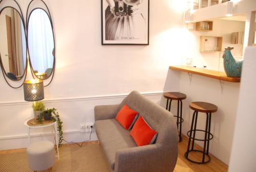 a living room with a gray couch and orange pillows at Le typique - coeur de ville in Toulouse