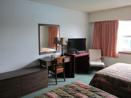 a hotel room with a desk and a bed and a mirror at Aleeda Motel in Prince Rupert
