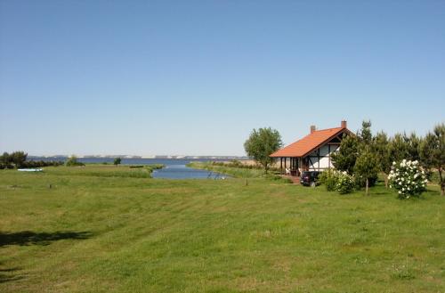 a house in a field next to a lake at Svenceles 25 sodyba Namas su pirtimi ir krantine in Svenele