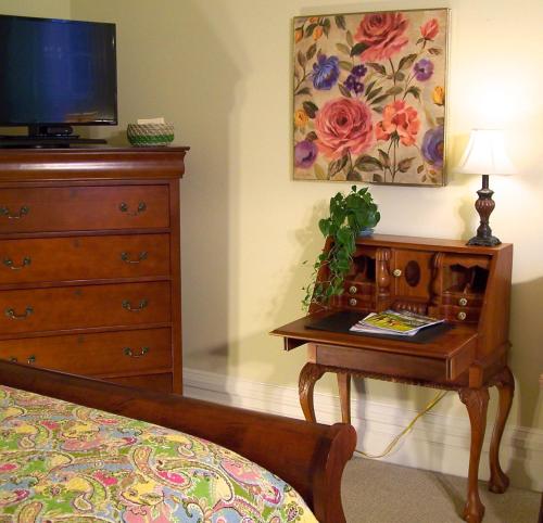 a bedroom with a bed and a dresser with a television at Lyndon House Bed & Breakfast in Lexington