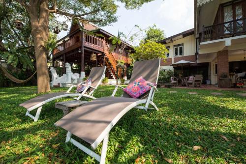 two lawn chairs sitting in the grass in front of a house at Phuttal Residence in Phra Nakhon Si Ayutthaya