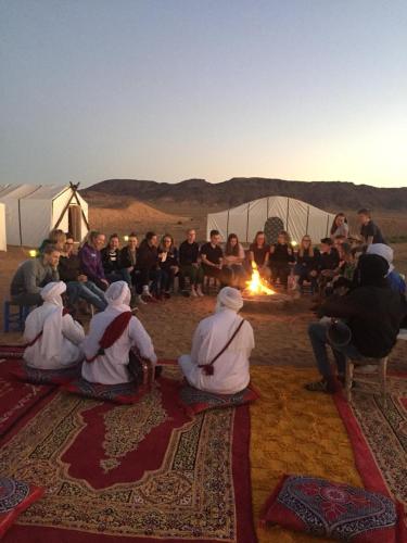 a group of people sitting around a fire in the desert at Bivouac Karim Sahara in Zagora