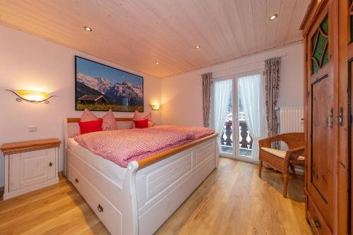 ミッテンヴァルトにあるFerienwohnung Sonnenhäuslのベッドルーム(赤い枕の大きな白いベッド付)