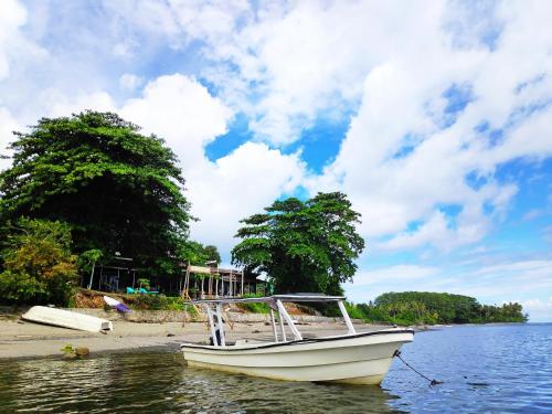 a boat sitting in the water on a beach at Sanctum Una Una Eco Dive Resort in Pulau Unauna