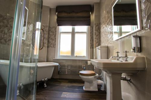 a bathroom with a sink and a toilet and a tub at Kings Park Hotel in Retford