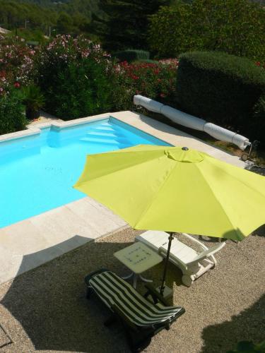 un parasol jaune et une chaise à côté de la piscine dans l'établissement La Quiétude, à Peymeinade