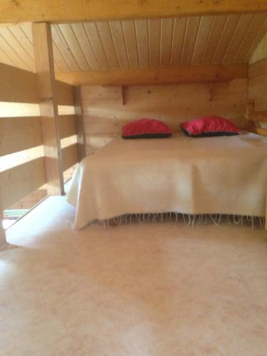 Una cama en una habitación de madera con almohadas rojas. en Les Marmottes, en Excenevex