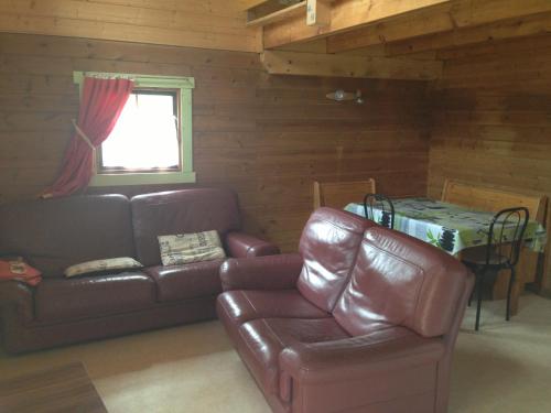 ein Wohnzimmer mit einem Ledersofa und einem Tisch in der Unterkunft Les Marmottes in Excenevex