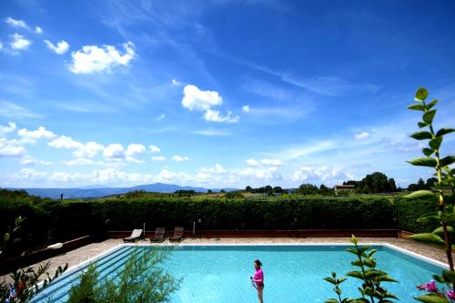 Apartment with privat garden في Montegabbione: امرأة تقف أمام حمام السباحة