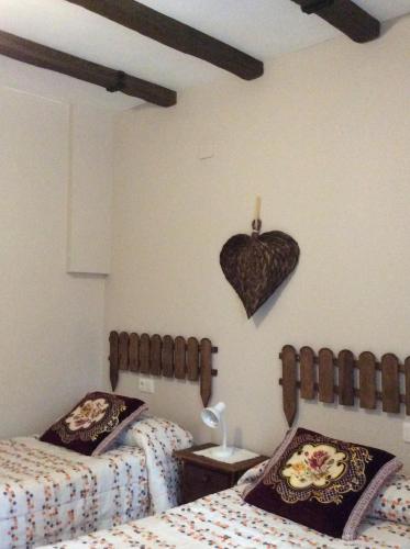 a bedroom with two beds and a heart on the wall at Apartamento Rural Castildetierra in Arguedas