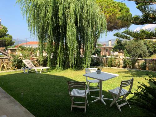 a table and chairs in a yard with a tree at Wooden Roof Apartment in Lixouri