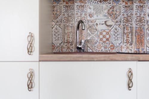 a bathroom with a sink with a mosaic wall at M.K. Apartments in Vilnius