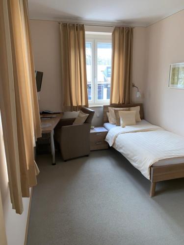 a bedroom with two beds and a desk and a window at Hotel Donau in Donauwörth