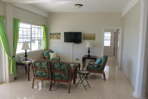 a living room with chairs and a table and a tv at Villa Sans Souci in Vieux Fort