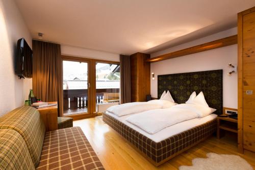 a bedroom with a large bed and a large window at Hotel Sandhof in Lech am Arlberg