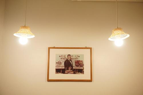two lights on a wall with a picture of a man at Khoksametchun Hostel in Hat Yai