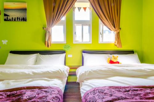 two beds in a room with green walls and windows at 梅花湖-陽光屋民宿 in Dongshan