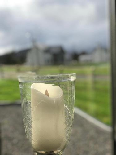 a candle in a glass container with a field in the background at Beechwood 4, Kenmare Luxurious Living in Killowen