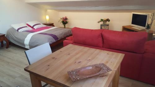 - un salon avec un canapé rouge et un lit dans l'établissement Location studio Grau du Roi Mas des Marines Piscine, au Grau-du-Roi