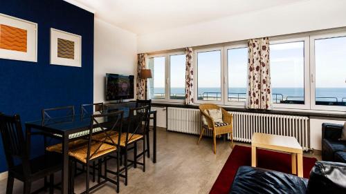 a living room with a table and chairs and windows at Apartment Valdemosa in De Haan
