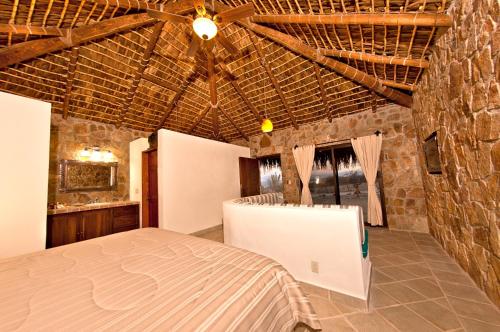 ein Schlafzimmer mit einem Bett und einer Steinwand in der Unterkunft Palapas La Choya in La Ventana