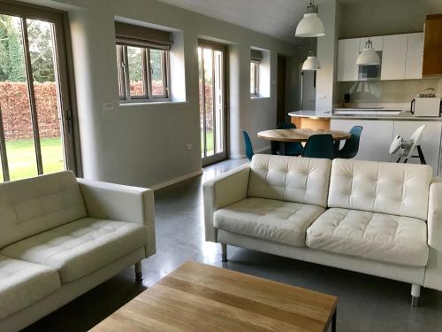 a living room with two white couches and a table at Bury Knowle Stables in Oxford