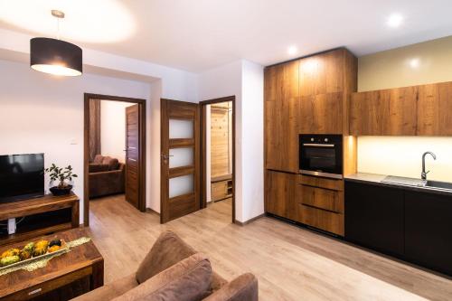 une cuisine avec des placards en bois et un salon dans l'établissement Newly renovated, Full Equipped and Quiet Apartment, à Trnava