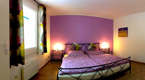 um quarto com uma cama com uma parede roxa em Uns' Husing em Marienfelde